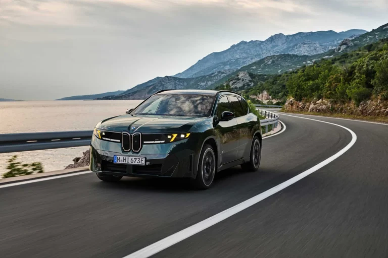 深綠色BMW iX3 M60 xDrive純電SUV在濱海道路行駛