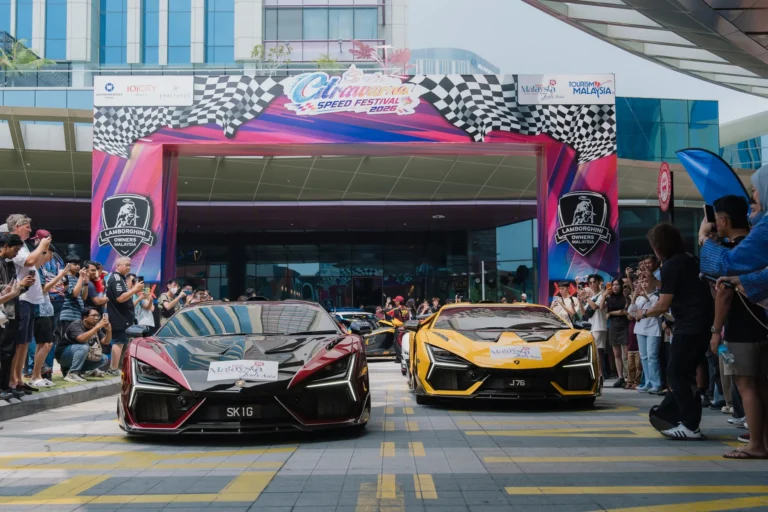 兩輛不同顏色的Lamborghini經過Citrawarna Speed Festival出發拱門，現場有觀眾及馬來西亞旅遊宣傳標誌