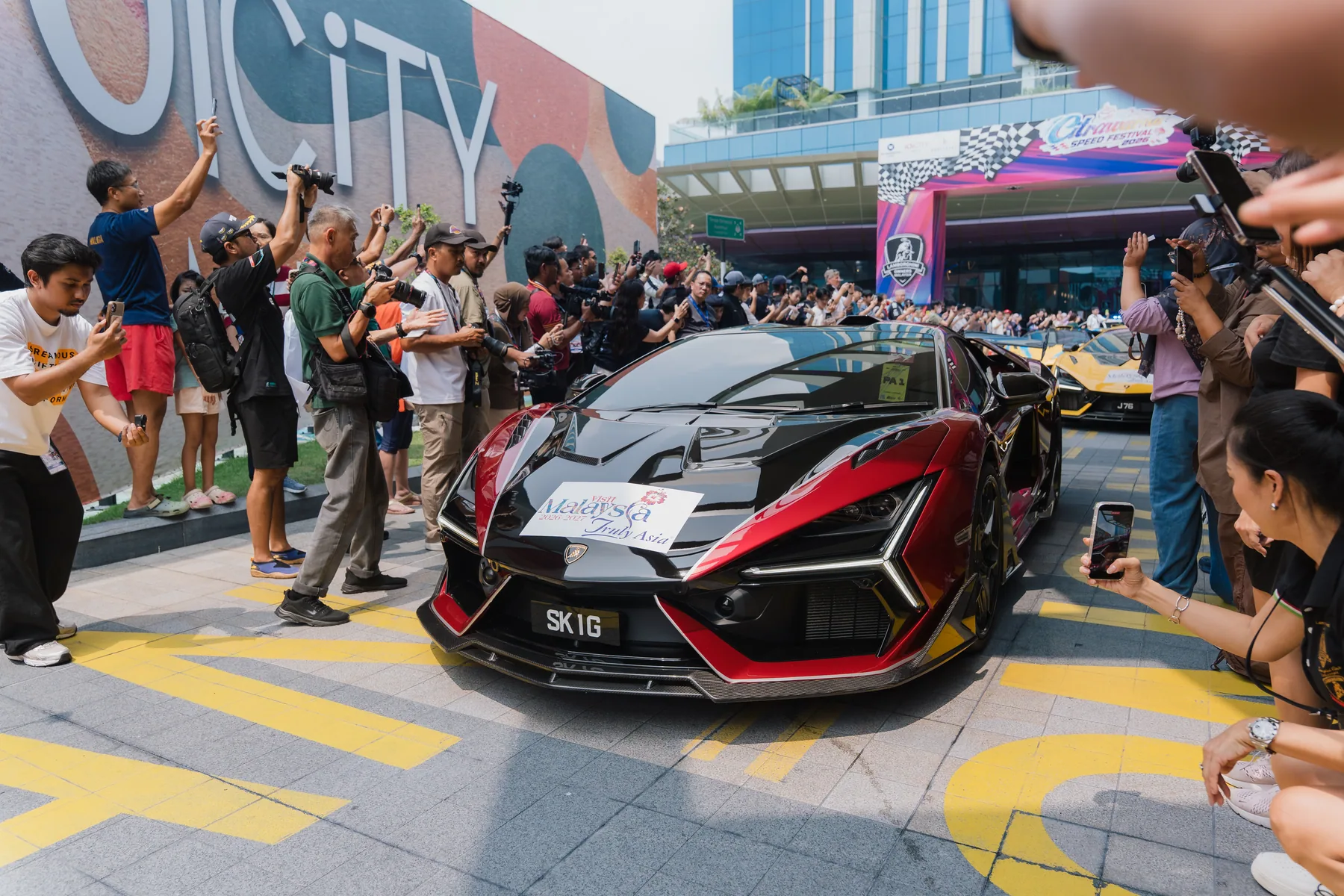 一輛紅黑色Lamborghini在布城IOI City Mall啟程,兩側有人群拍攝